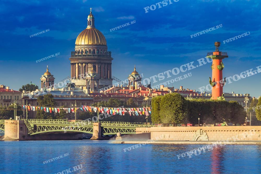 На фотографии изображены Исаакиевский собор и Ростральная колонна в Санкт-Петербурге в ясный летний день. Фото может использоваться для туристических буклетов, открыток и рекламных материалов.